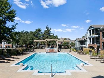 A large swimming pool surrounded by trees and a building.